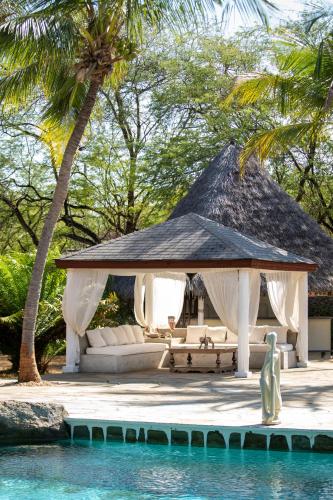 a pavilion with a couch and a table next to the water at Lion in the Sun Boutique Hotel & Spa in Malindi