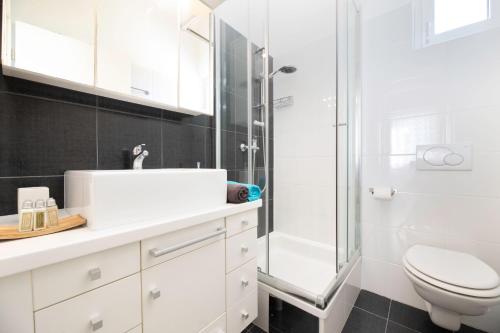 a white bathroom with a shower and a toilet at Apartment Arte Vrbnik in Vrbnik