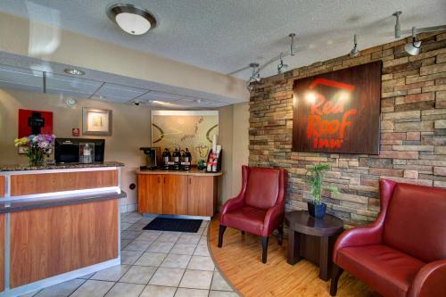 a bar in a restaurant with two red chairs at Red Roof Inn Pensacola - I-10 at Davis Highway in Pensacola