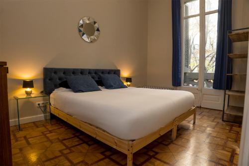 a bedroom with a large white bed with blue pillows at Cami Gallery Barcelona in Barcelona