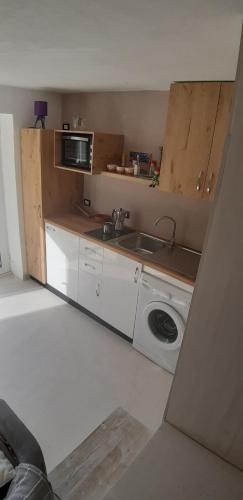 a kitchen with a sink and a washing machine at Les Villas de Qeparo in Qeparo