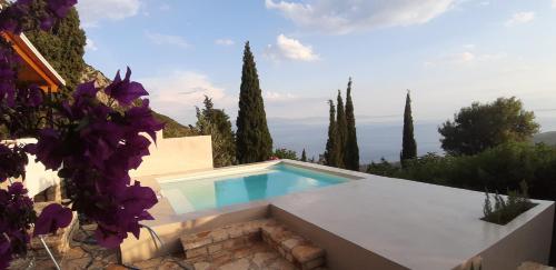 a swimming pool in a villa with purple flowers at Les Villas de Qeparo in Qeparo
