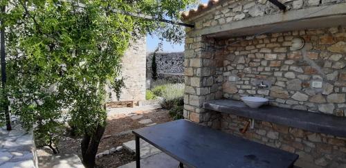 a stone wall with a picnic table in a yard at Les Villas de Qeparo in Qeparo