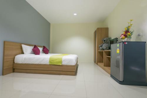 a bedroom with a bed and a refrigerator in it at Tha-ruea Residence in Thalang