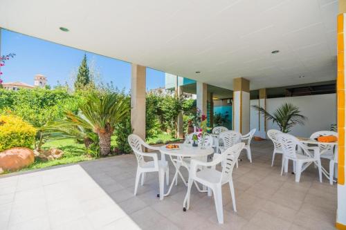 a patio with white tables and white chairs at BRESSOL DELUXE Apartments in Port de Pollensa