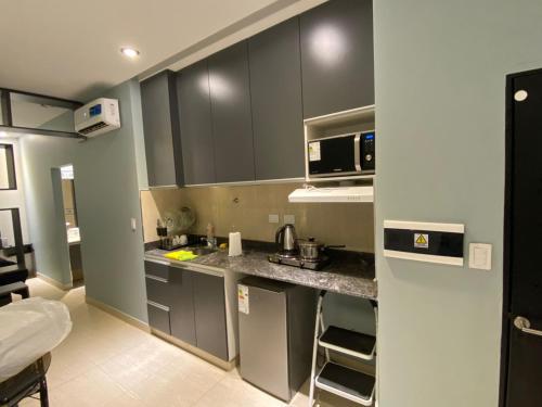 a kitchen with gray cabinets and a sink and a microwave at Departamentos Muskuy - Salta Capital in Salta