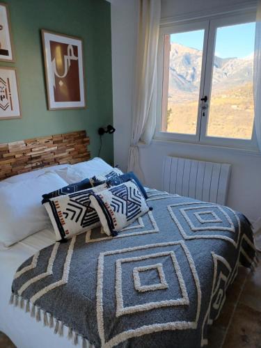 une chambre avec un lit avec une couverture et une fenêtre dans l'établissement Maison Bohème Vesubie, à La Bollène-Vésubie