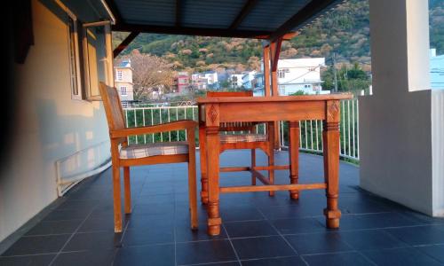 a wooden table and two chairs on a balcony at Colonial Cocoon Studio and Apartement in La Gaulette