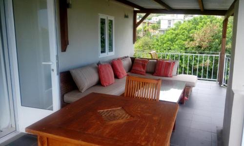 a porch with a couch and a table on a balcony at Colonial Cocoon Studio and Apartement in La Gaulette