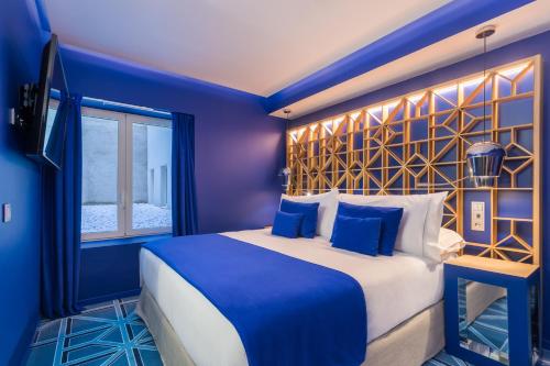a blue bedroom with a large bed and a window at Room Mate Macarena, Madrid Gran Vía in Madrid