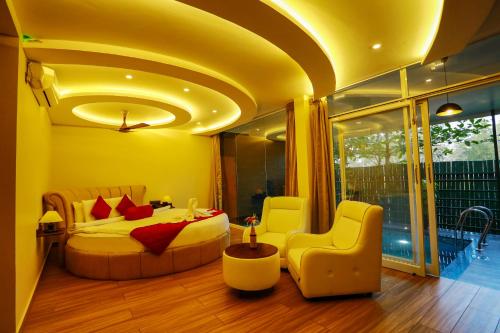 a bedroom with a bed and chairs in a room at Kuruva Island Resort And Spa - By KABINI BREEZE in Mananthavady