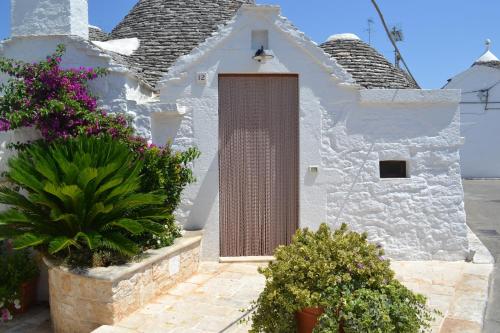 a white church with a door and some plants at Trulli Aia Piccola in Alberobello
