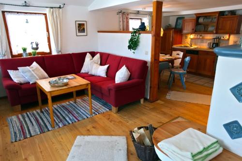 a living room with a red couch and a table at Dandl-Hof in Ruhpolding