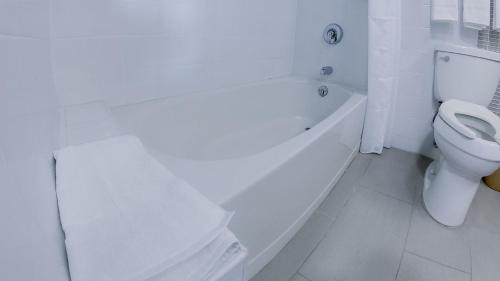 a bathroom with a white tub and a toilet at Royal Delonix in Penuelas