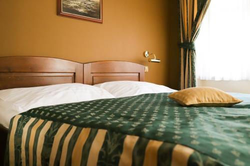 a bed with a green and white blanket and a window at U Schnellu in Prague