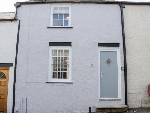 a white house with a white door and windows at Clock cottage in Conwy