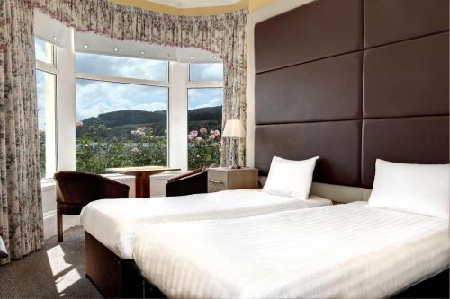 two beds in a hotel room with a large window at SGE Esplanade Hotel in Dunoon