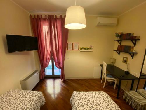 a room with two beds and a desk and a table at La Casa di Amici Miei in Cremona