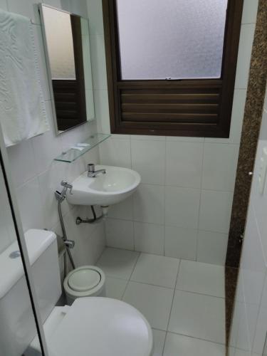 a white bathroom with a toilet and a sink at Hotel Paris in Sao Paulo