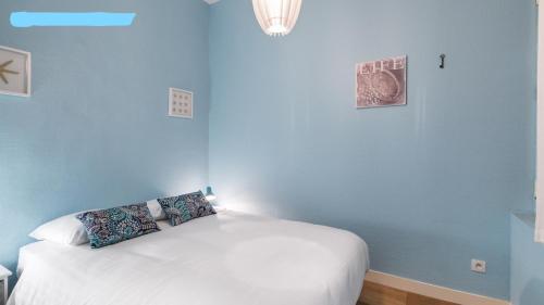 - une chambre avec un lit blanc et un mur bleu dans l'établissement Le Kervegan, à Nantes
