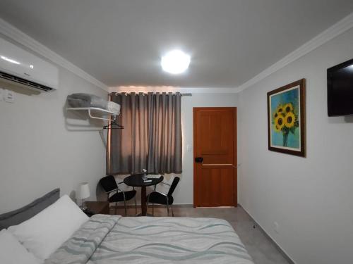 a bedroom with a bed and a table with chairs at Ipê Suítes in Domingos Martins