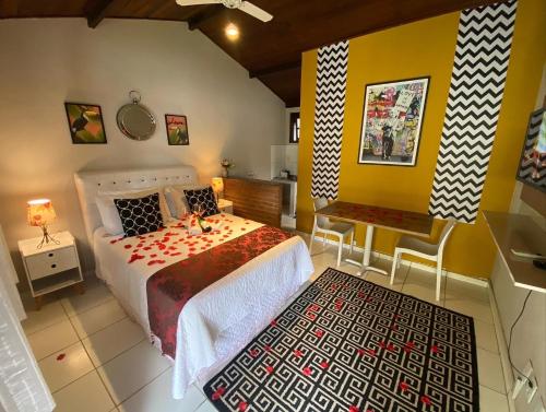 a bedroom with a bed and a table and a bench at Vila Noel Centro in Penedo