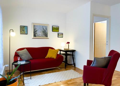 a living room with a red couch and two chairs at Apartment Mletačka in Zagreb