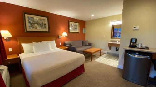 a hotel room with a bed and a chair at Sahara Courtyard Inn & Suites Osoyoos in Osoyoos