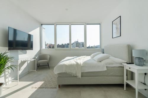 een witte slaapkamer met een bed en een televisie bij Sophienne Apartments in Wenen