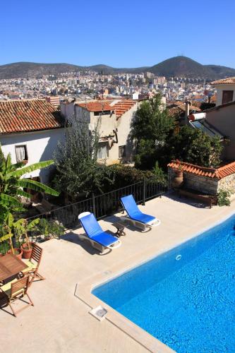 a swimming pool with two blue chairs next to a house at Villa Konak Hotel in Kusadası