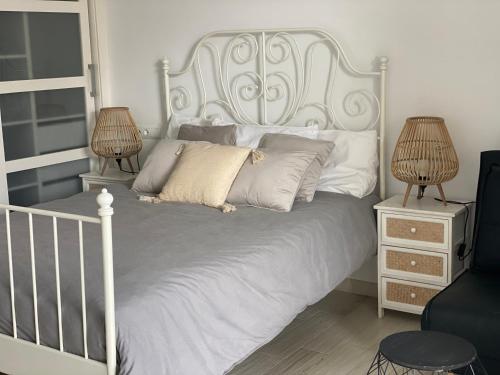 a white bed with a white headboard and two lamps at Benal Beach Apartments in Benalmádena