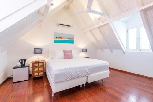 een witte slaapkamer met een bed en een plafondventilator bij Scuba Lodge & Suites in Willemstad