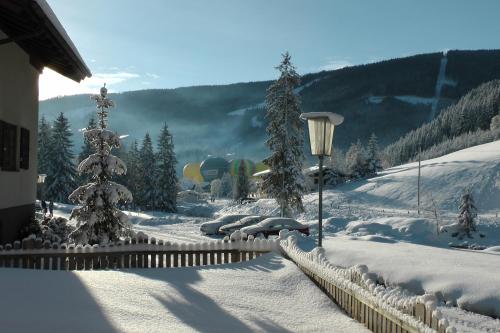 a snow covered yard with a fence and a lamp at Haus Filzmoos in Filzmoos
