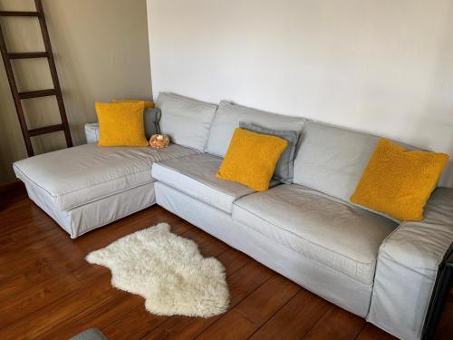 a white couch with yellow pillows in a living room at CHAPEAUVEAU Gîte - b&b - Events in Helecine