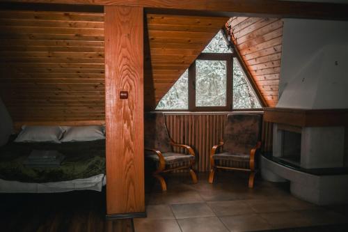a bedroom in a log cabin with a bed and a chair at Hanul Vanatorului in Gureni