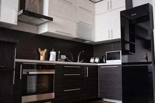 a kitchen with black cabinets and white appliances at RentWill apartments Valley of Roses in Sectorul Botanica