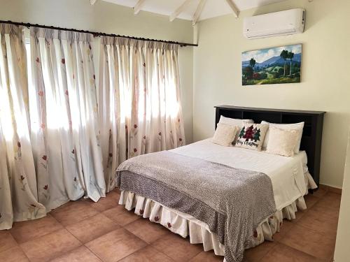 1 dormitorio con 1 cama con cortinas blancas en El Yaguacil Aparta Hotel, en Jarabacoa