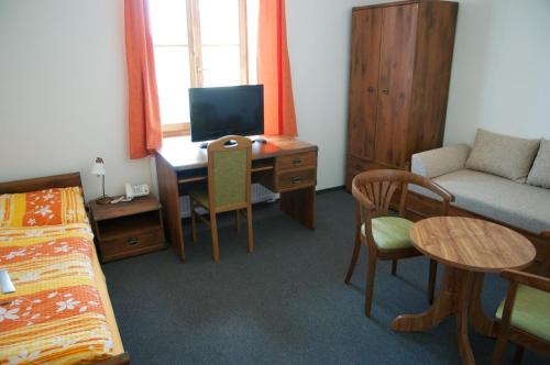 a room with a desk with a computer and a bed at Penzion Pod Zámkem in Zruč nad Sázavou