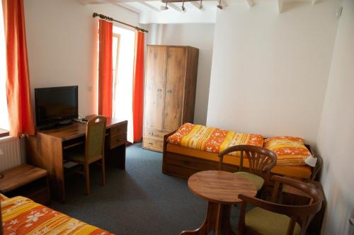 a room with a bed and a desk with a table at Penzion Pod Zámkem in Zruč nad Sázavou