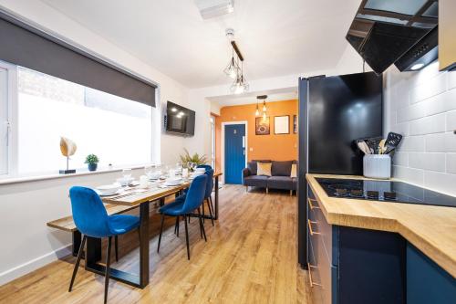 a kitchen and dining room with a table and blue chairs at 7 bedroom house ENSUITE Rooms, fully equipped kitchen, free WIFI, TVs in all rooms CITY CENTRE CLOSE TO A46 Inspire Homes in Coventry