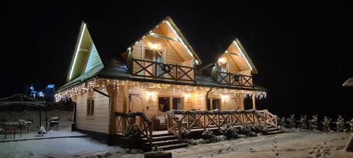 a house with christmas lights on the side of it at Bieszczadzkie Chaty in Polańczyk