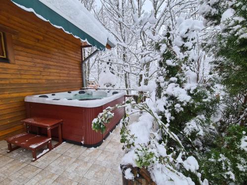 a hot tub on a patio with snow covered trees at House Poljana in Plitvička Jezera
