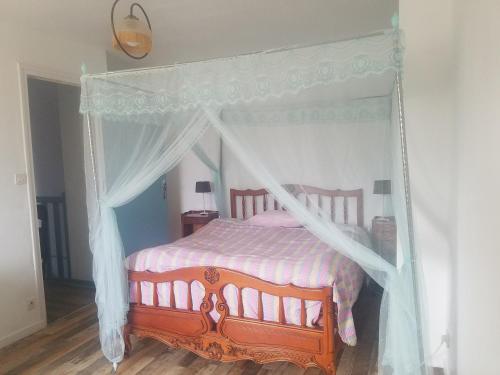 a bedroom with a canopy bed with a wooden floor at La clef des champs - Gîte 9 personnes entre Lyon et St-Etienne in Les Halles