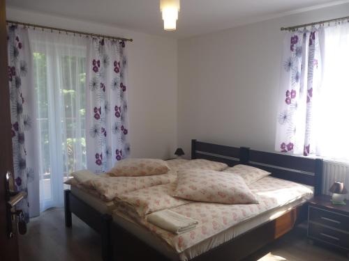 a bedroom with a bed with pillows and curtains at Ośrodek Wypoczynkowy Nad Stawem vis a vis Parku Zdrojowego z Tężnią Solankową - B&B Holiday Resort By The Lake - Erholungsheim Am See - Prázdninový dům U Jezera in Kudowa-Zdrój