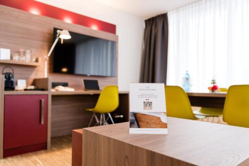 a room with yellow chairs and a table with a sign on it at Hotel Alte Werft in Papenburg