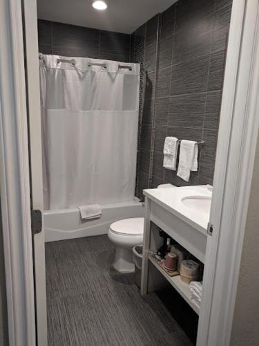 a bathroom with a toilet and a shower and a sink at American Inn Downey in Downey
