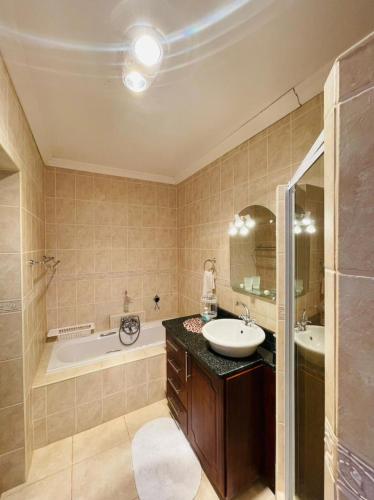 a bathroom with a tub and a sink and a bath tub at Casa Alegre Guesthouse in Southbroom