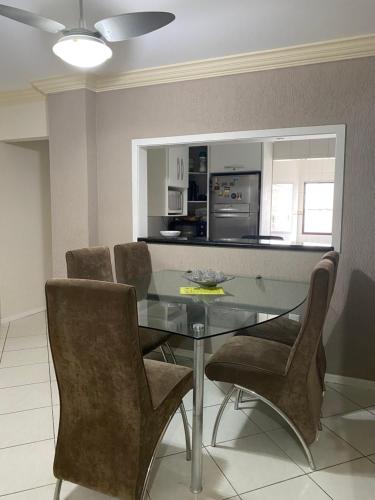 Un comedor con una mesa de cristal y sillas. en LINDO APARTAMENTO EM MEIA PRAIA-1 quadra do mar! Melhor localização!, en Itapema