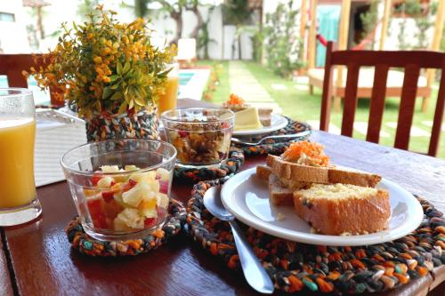 uma mesa de madeira com um prato de comida e bebidas em Kai'ala Pousada em São Miguel do Gostoso