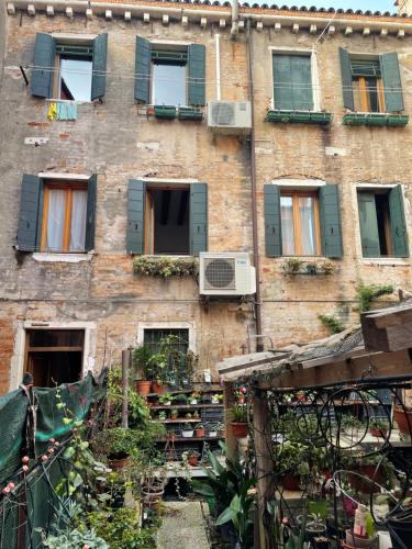 an old brick building with windows and plants at Ca Marga Cannaregio - Central Venetian Style 2 bedroom apartment in Venice